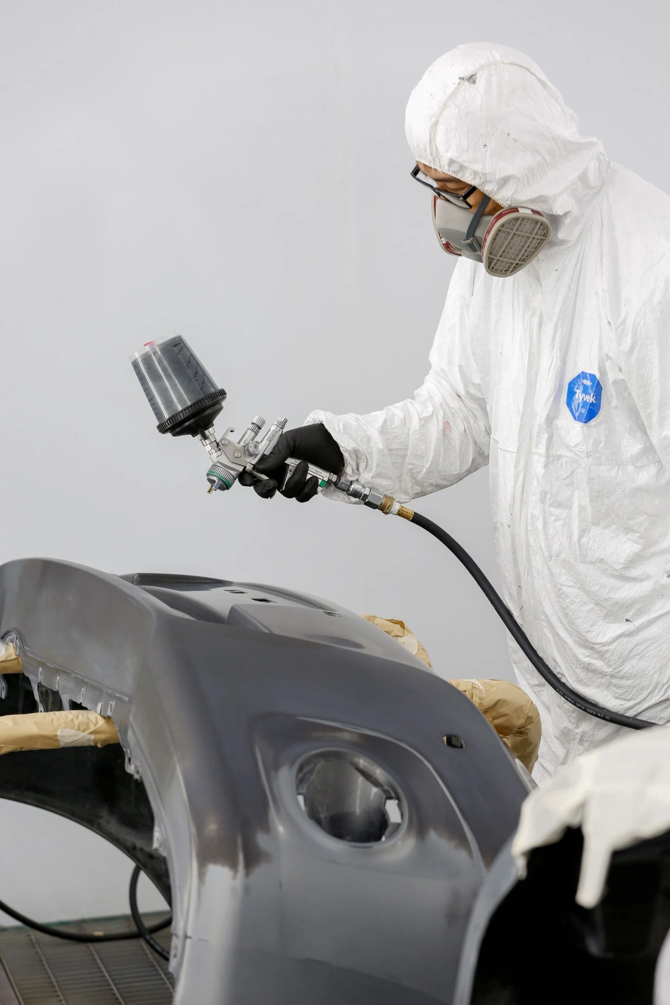 Técnico aplicando pintura sobre una pieza de carrocería
